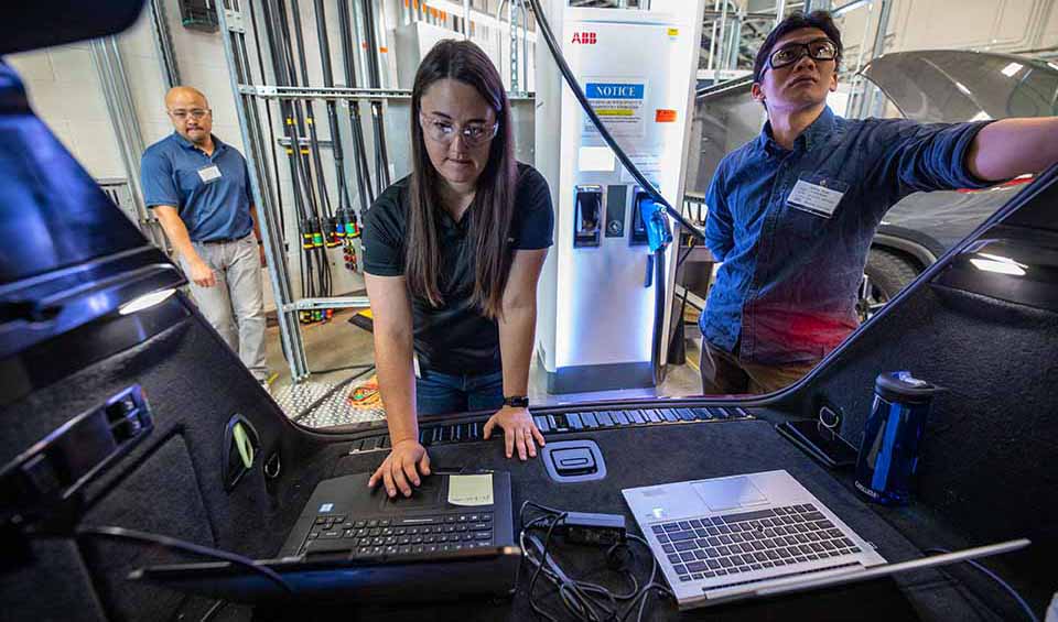 Researchers in a lab evaluating the cybersecurity of an electric vehicle grid system.