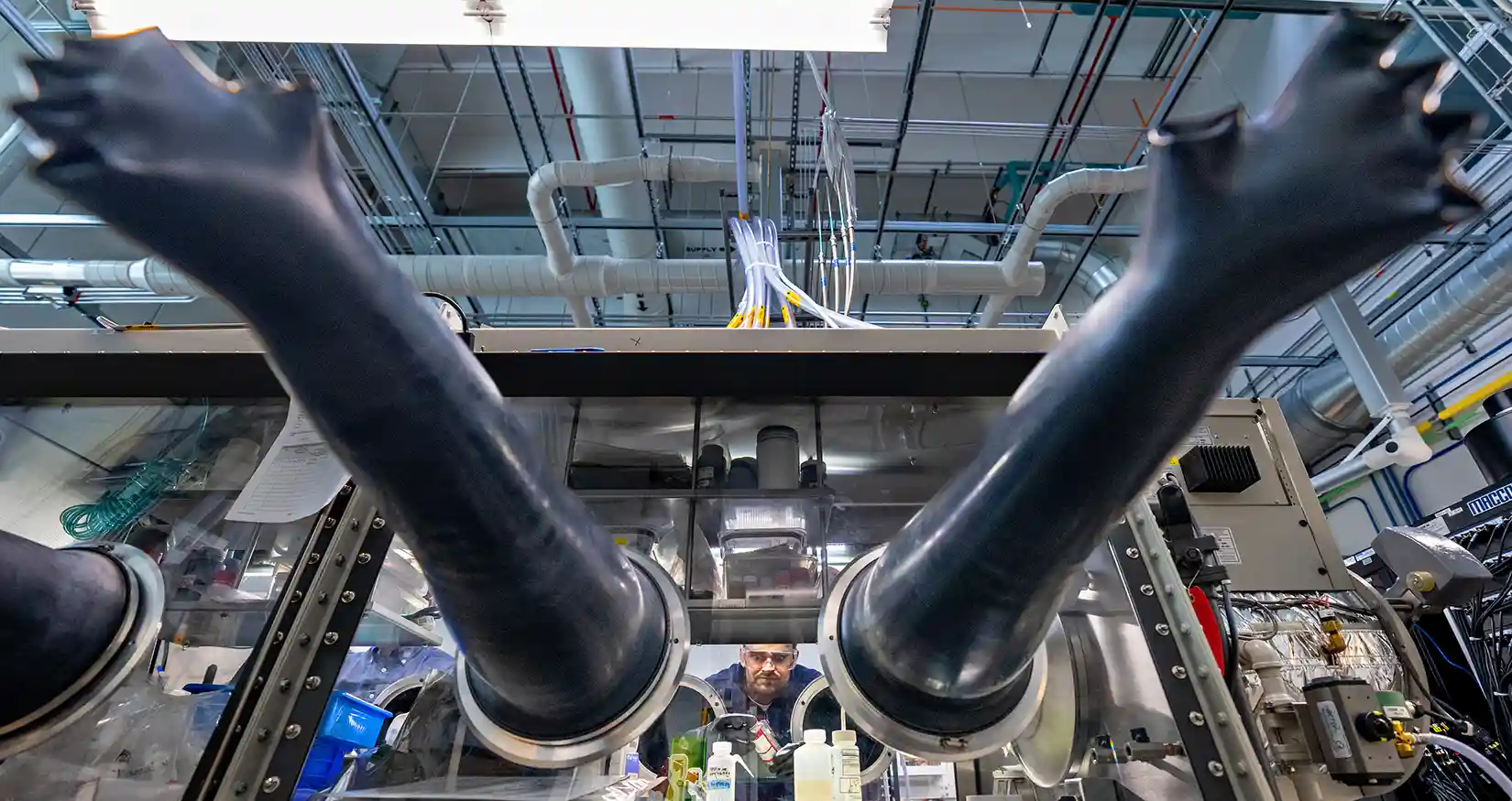 Researcher in a lab works in a glove box, analyzing battery assembly