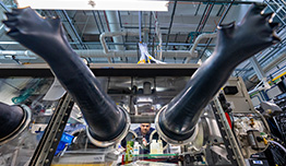 Researcher in a lab works in a glove box, analyzing battery assembly