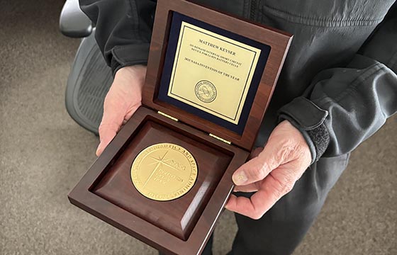 Hands holding the NASA 2025 Invention of the Year award plaque.