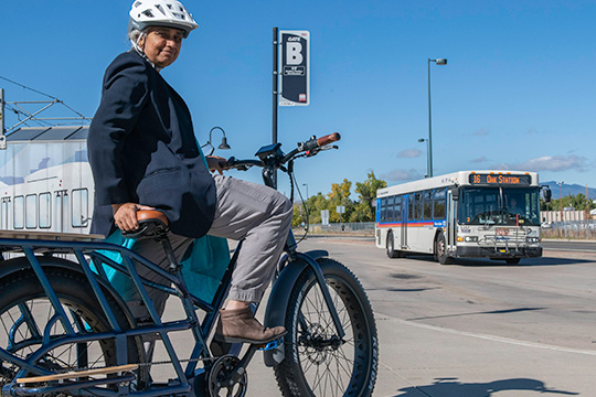 Woman rides an electric bicycle at the Oak Street RTD rail stop.