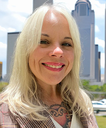 A headshot of a woman with shoulder-length white-blond hair, wearing a blazer.