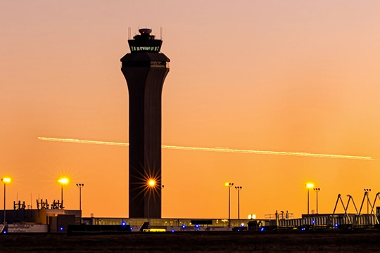 An air traffic control tower at sunset.