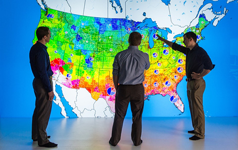 Photo of researchers looking at a large, colorful map of the United States.