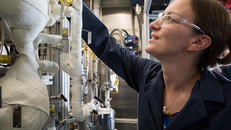 Photo of a researcher works with a plug flow reactor in a lab